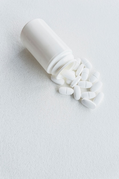 Pills spilling out from white plastic bottle