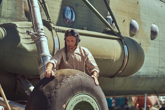 Pilot or mechanic in uniform and flying helmet washes large military helicopter.