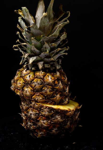 Pineapple cut in half on a black