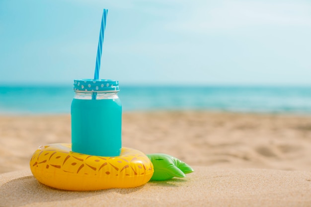 Free photo pineapple juice with an inflatable at the beach