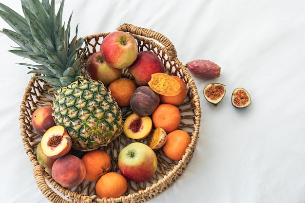 Pineapple and other exotic fruits in a basket on a white background top view