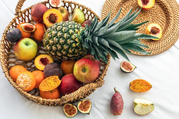 Pineapple and other exotic fruits in a wicker basket on a white background