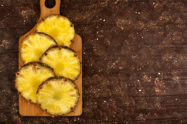 Pineapple pieces sliced fresh ripe juicy a top view on brown wooden desk and rustic background