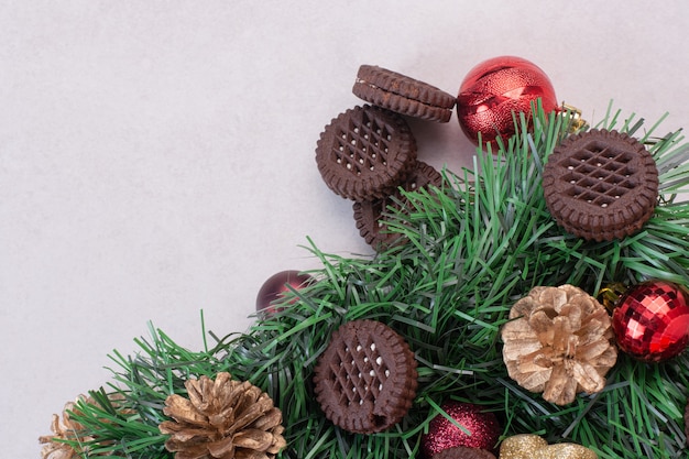 Free photo pinecones with christmas balls and cookie on white surface