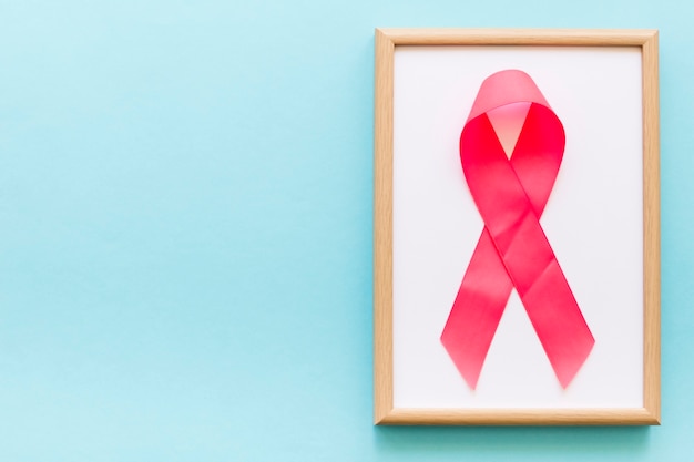 Free photo pink awareness ribbon on white frame over the blue background