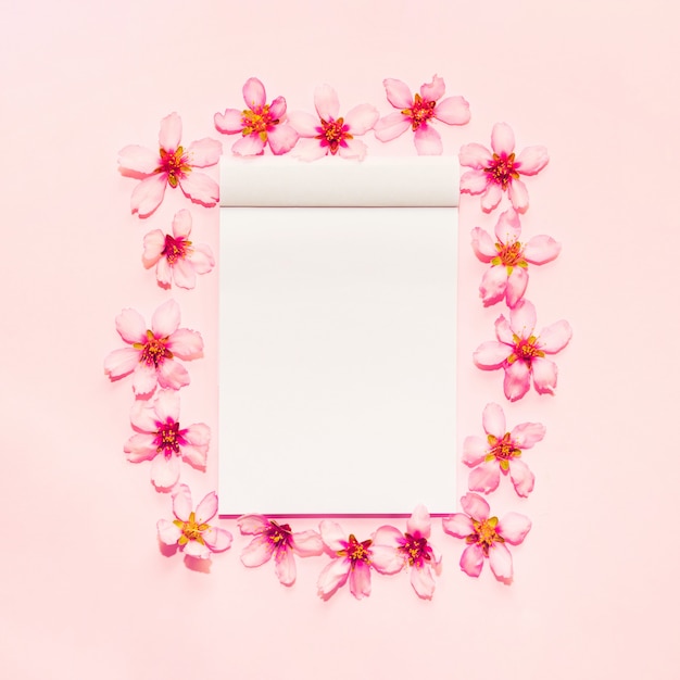 Free Photo pink background with notebook around flowers 