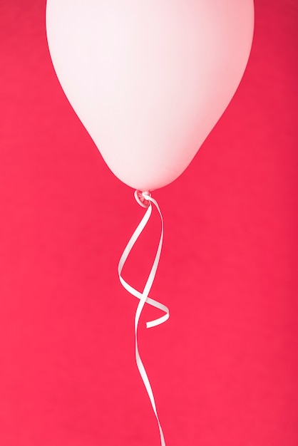 Free Photo pink balloon with ribbon on red background