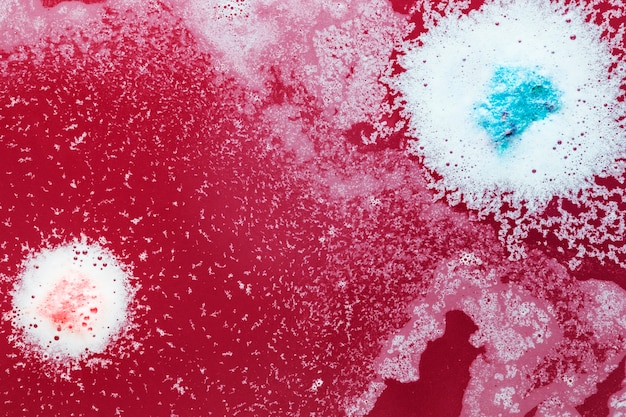 Pink and blue drops on red water