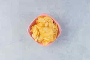 Free photo pink bowl of delicious crunchy chips on stone background.