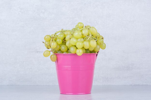 A pink bucket full of green sweet grapes