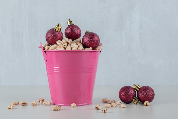 A pink bucket full of healthy cereals with Christmas balls .