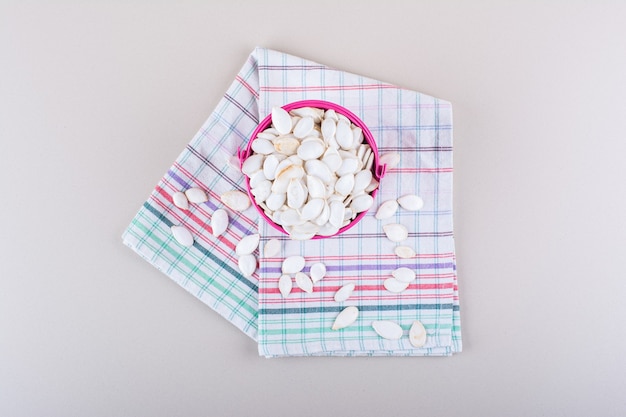 Pink bucket full of organic pumpkin seeds on white background. High quality photo