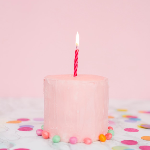 Free photo pink cake with lit candle