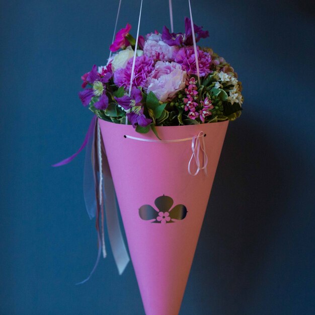 A pink cardboard bouquet of seasonal summer flowers hanged on a studio wall