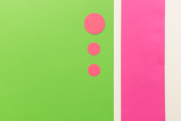 Pink circle shape papers in different sizes arranged on green card paper