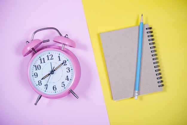 Free photo pink clock on the colorful background, education concept