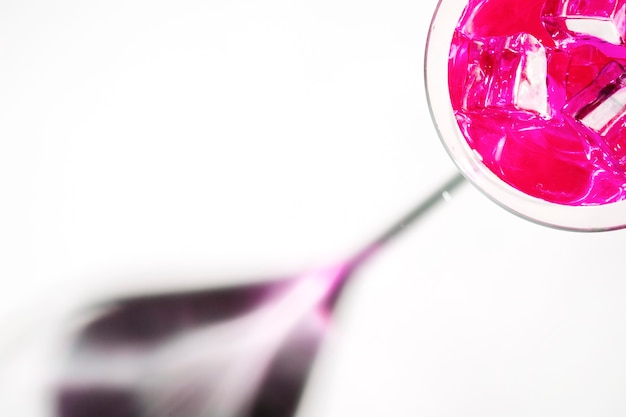 Pink cocktail with ice cubes in the martini glass on white background