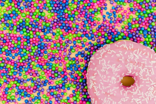 Free Photo pink donut on sprinkles ball background