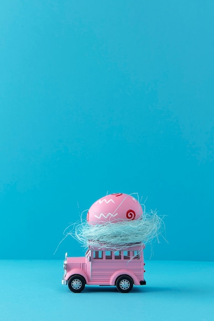 Free photo pink easter car with egg and blue background