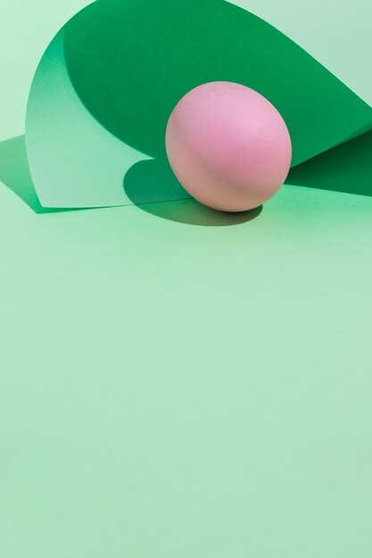 Pink Easter egg under rolled paper sheet on table