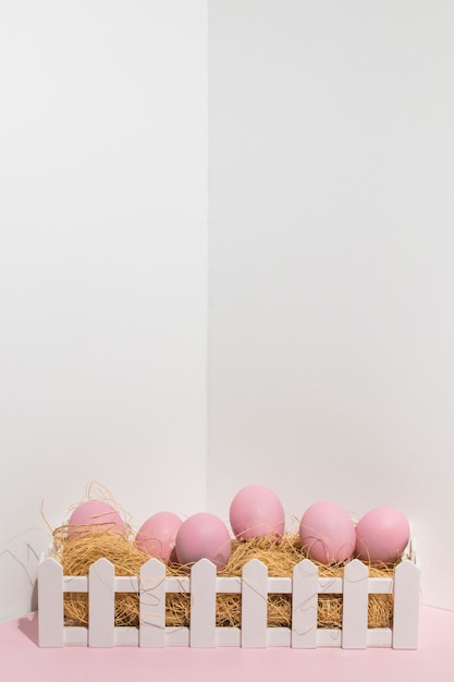 Pink Easter eggs on hay in white box