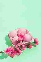 Free photo pink easter eggs in rack with flowers on green table