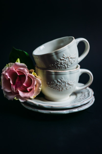 Free photo pink flowers lie on plate by two porcelain cups