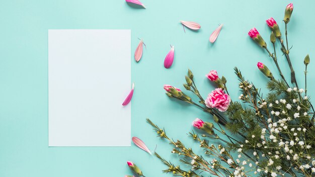 Pink flowers with blank paper on blue table