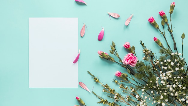 Pink flowers with blank paper on blue table