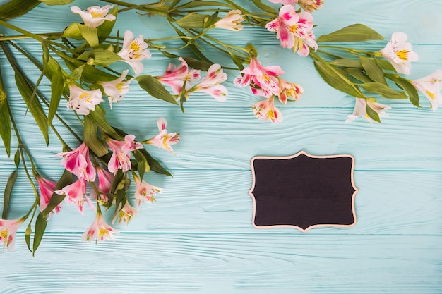 Free photo pink flowers with small chalkboard on table