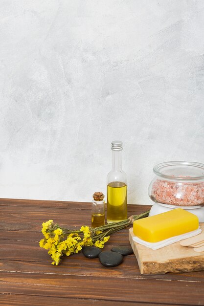 Pink himalayan salt jar; sponge; lastone; essential oil and limonium flowers on table