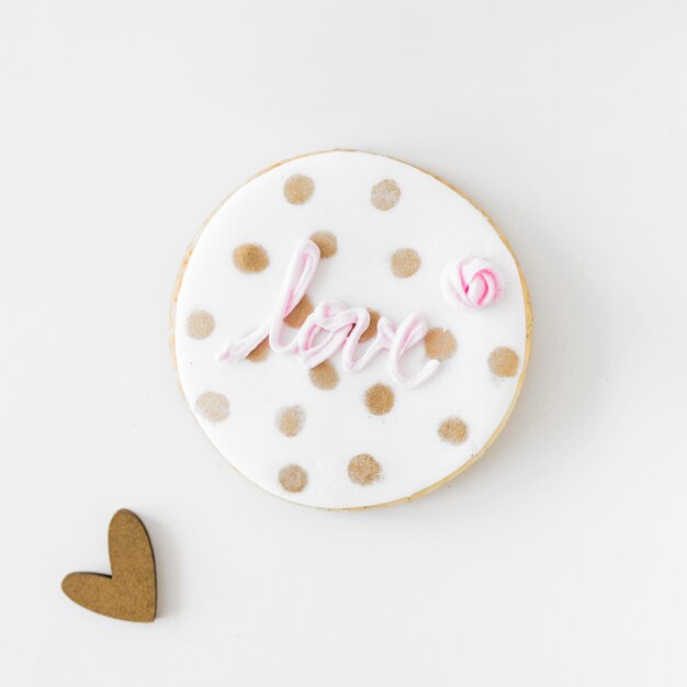 Pink love text on homemade cookie with heart shape over white background