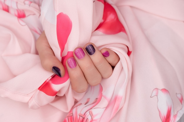 Pink nail design. Manicured female hand on pink background.