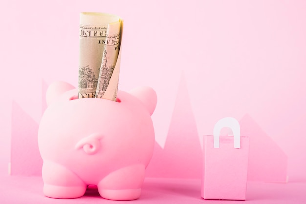 Free photo pink piggy bank with money and paper bag