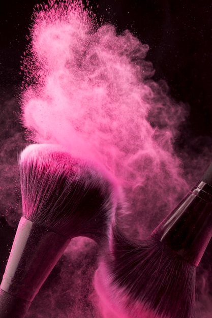 Free photo pink powder spread with brushes rubbing each other