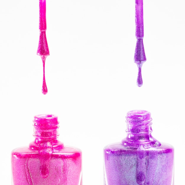 Free Photo pink and purple nail polish bottle on white background