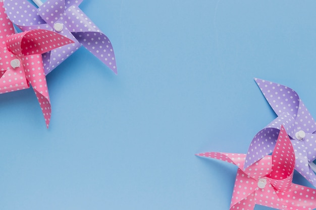 Pink and purple polka dotted pinwheel arrange at the corner of blue backdrop