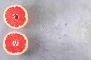 Free photo pink ripe grapefruit slices placed on a stone table.