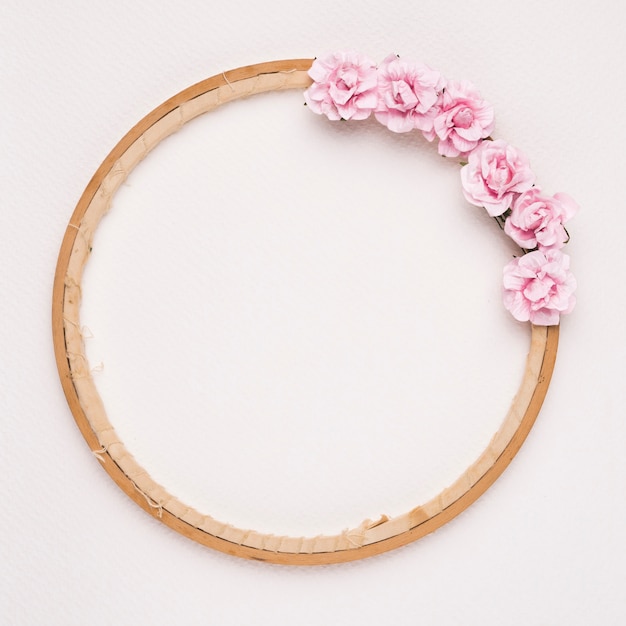 Free photo pink roses decorated on circular wooden frame against white backdrop