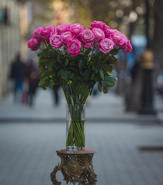 Pink roses inside a glass vase in the middle of the street