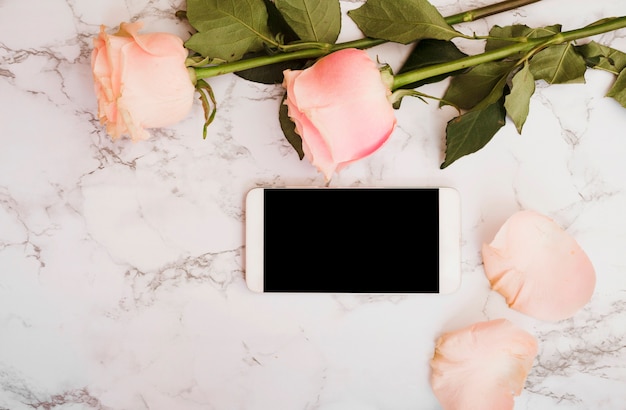 Free Photo pink roses with smart phone on marble textured background