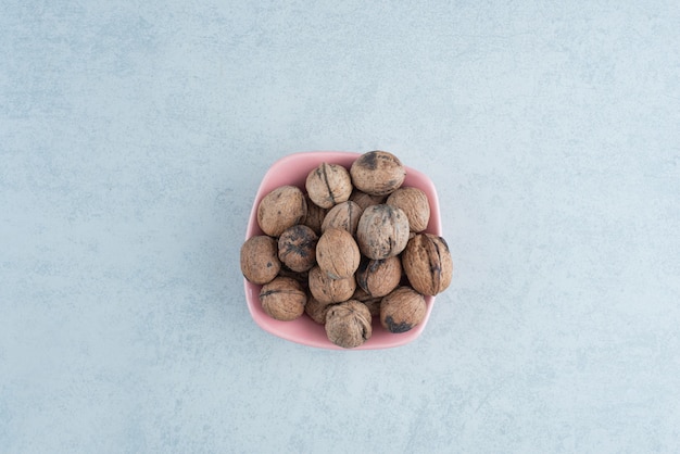 A pink small plate full of nuts on marble background. High quality photo