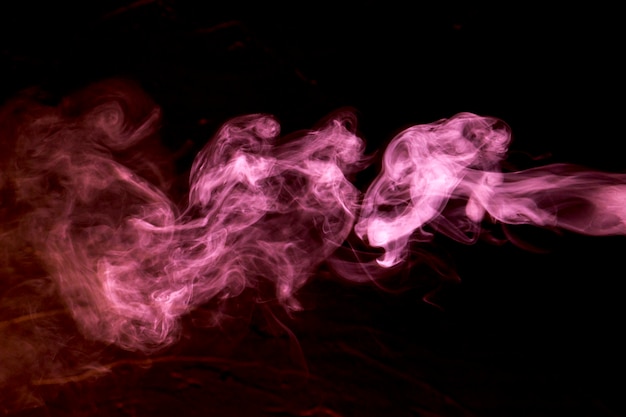 Pink smoke clouds over black background