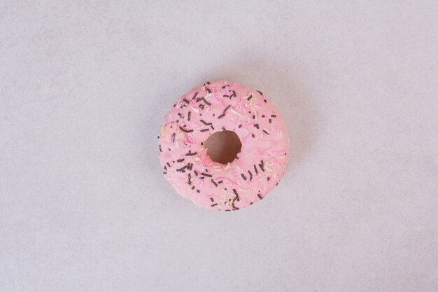 Pink sweet doughnut on white surface