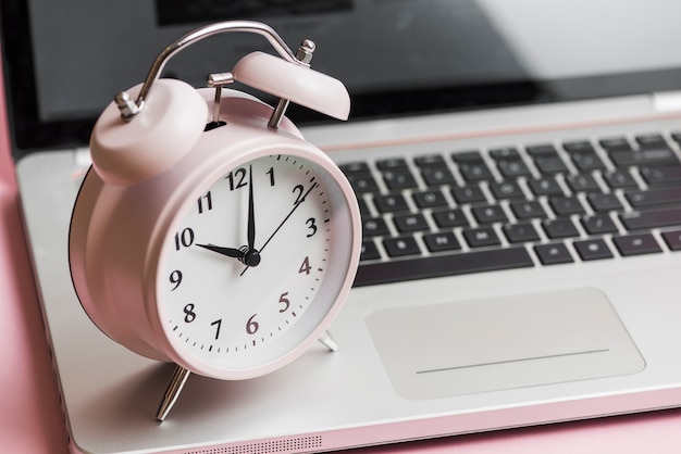 Pink vintage alarm clock on an open laptop