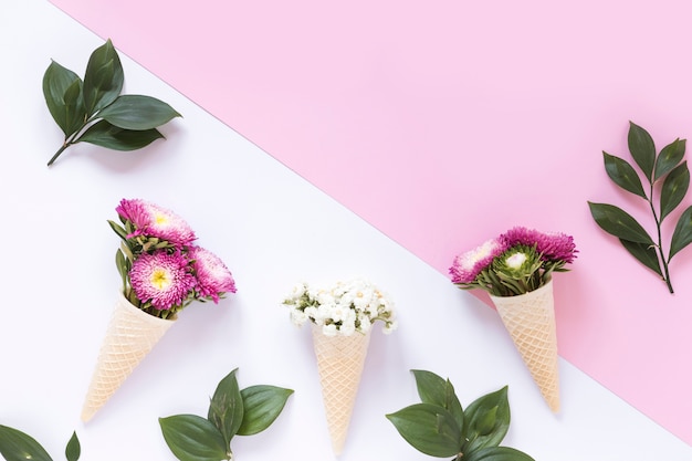 Pink and white flowers in waffle ice cream cone on dual surface