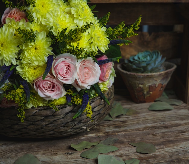 Pink and yellow flowers combination inside a bamboo vase.