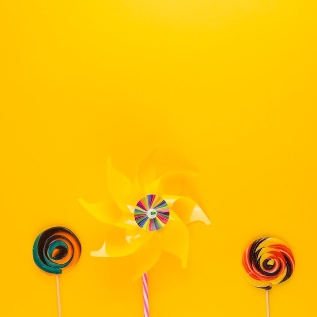 Free photo pinwheel with swirl lollipops on yellow backdrop