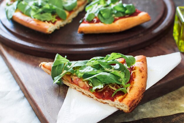 Pizza slice served on tissue paper over the chopping board