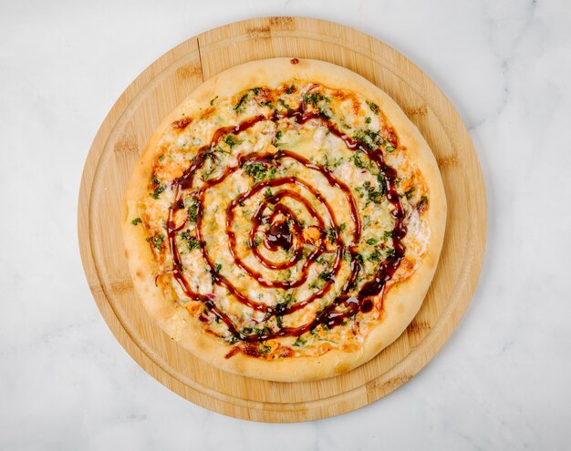 Pizza with herbs and red sauce on a wooden platter.